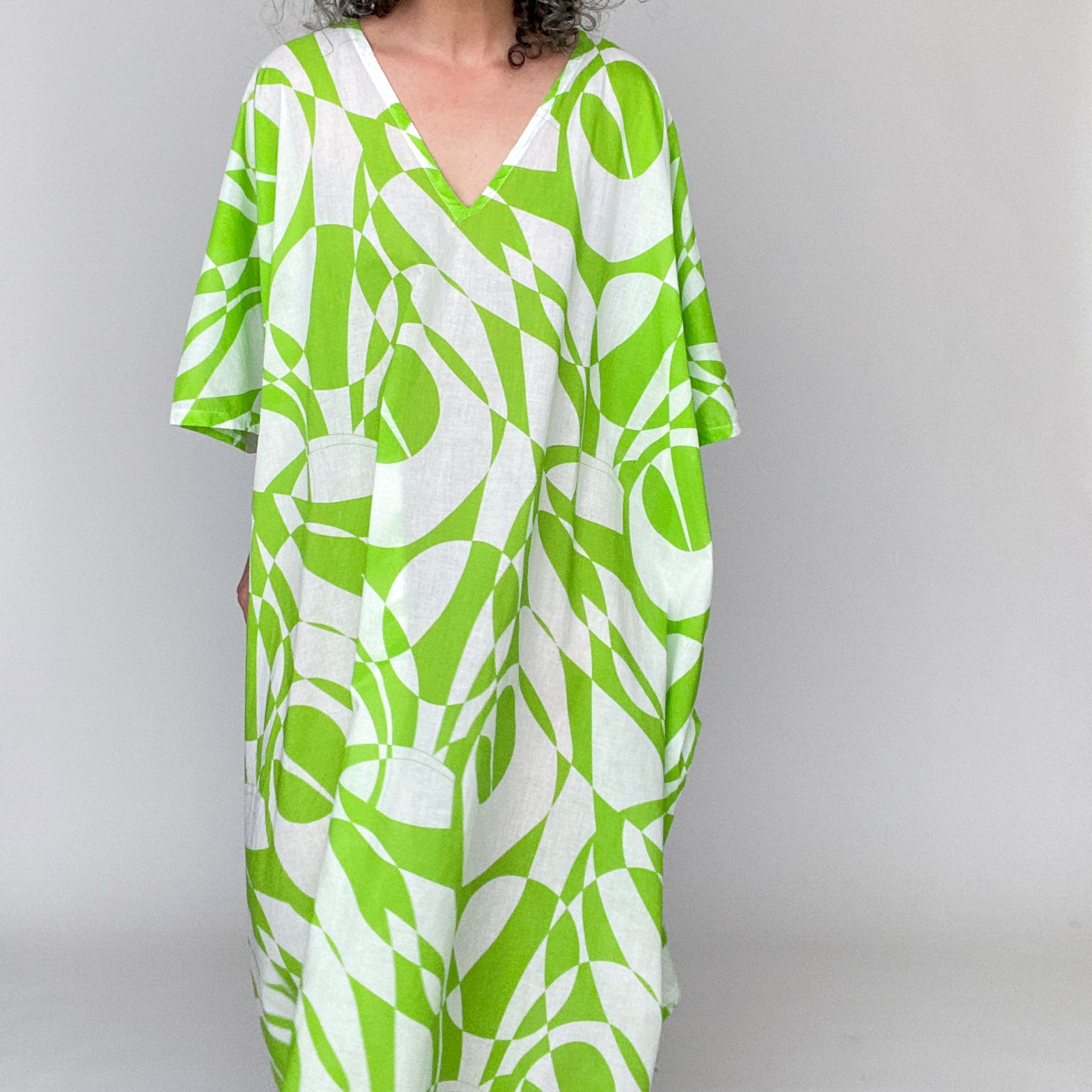 Close up of Mae in Color Number 42, a bright lime green and white geometric print, on the Mae caftan. 